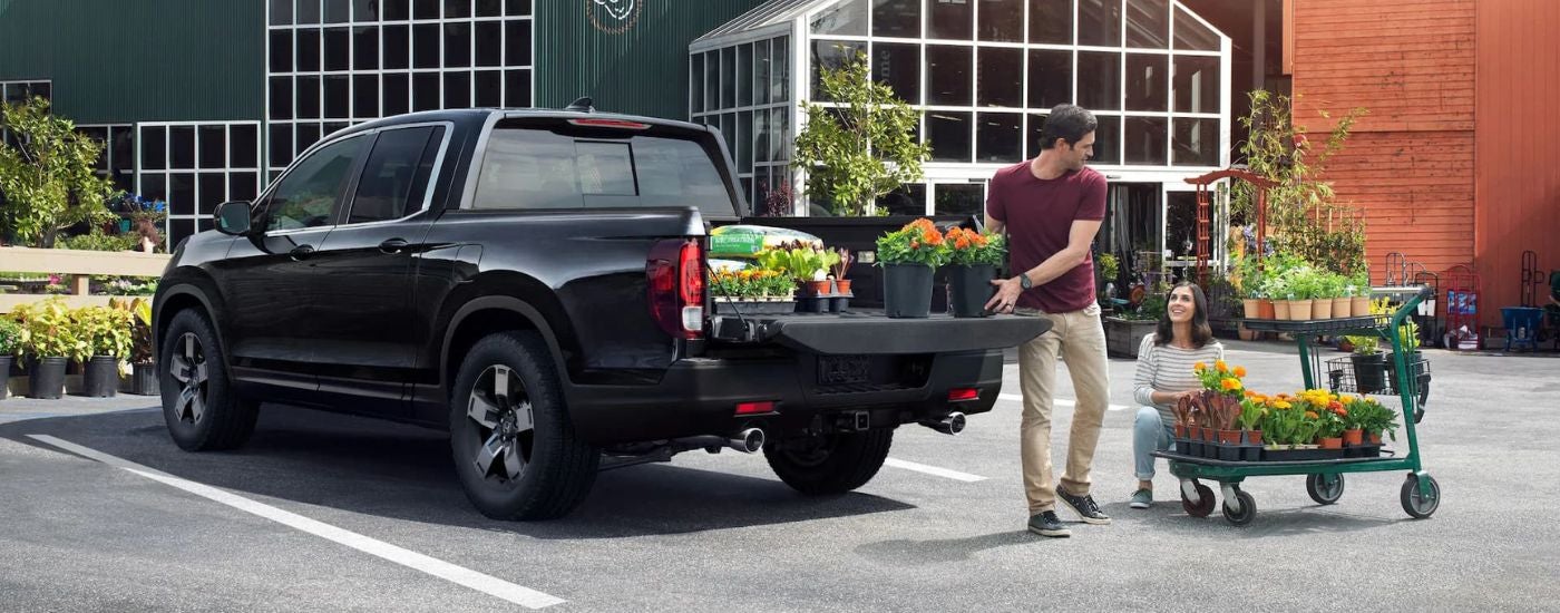 A person is shown loading plants into the bed of a 2024 Honda Ridgeline RTL.
