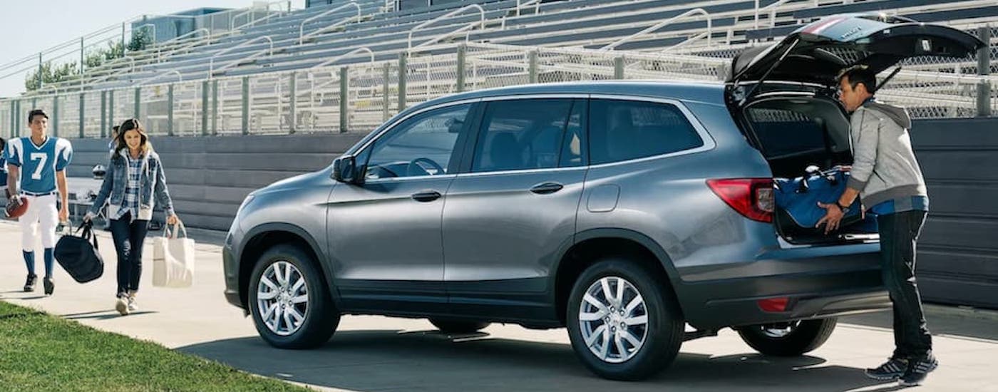 A silver 2021 Honda Pilot is shown from the rear at an angle with the hatch open after leaving a dealer that has used SUVs for sale near Andrews.