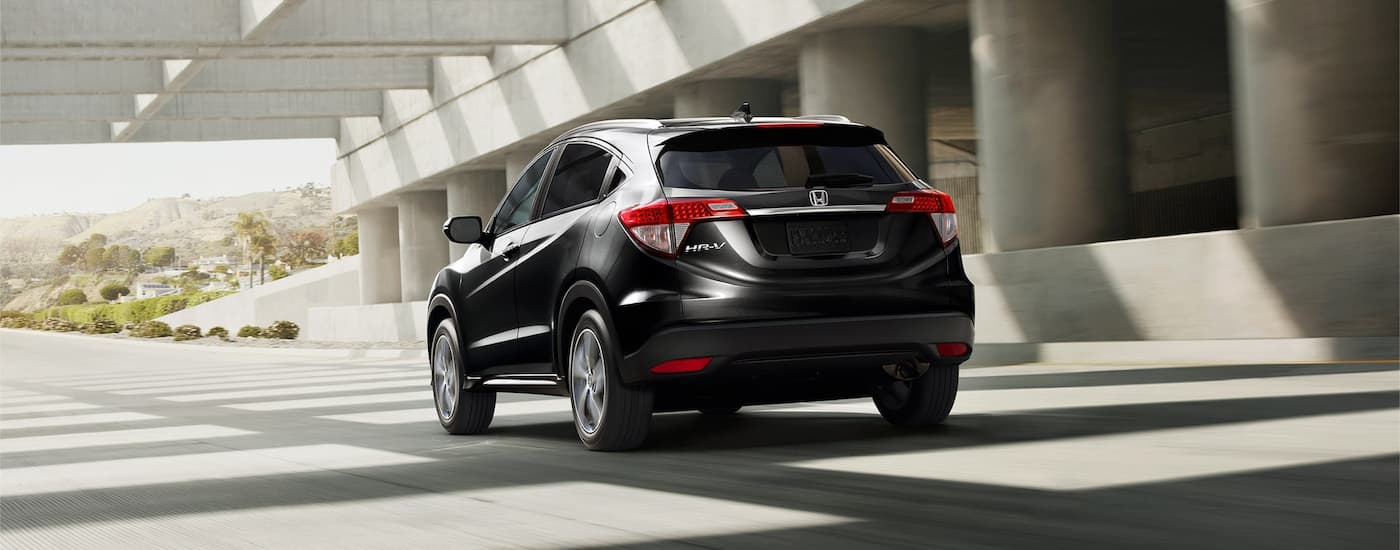 A black 2022 Honda HR-V is shown from the rear driving through a city.