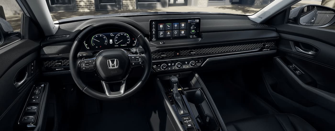 The black interior of a 2023 Honda Accord Touring shows the steering wheel and center console.