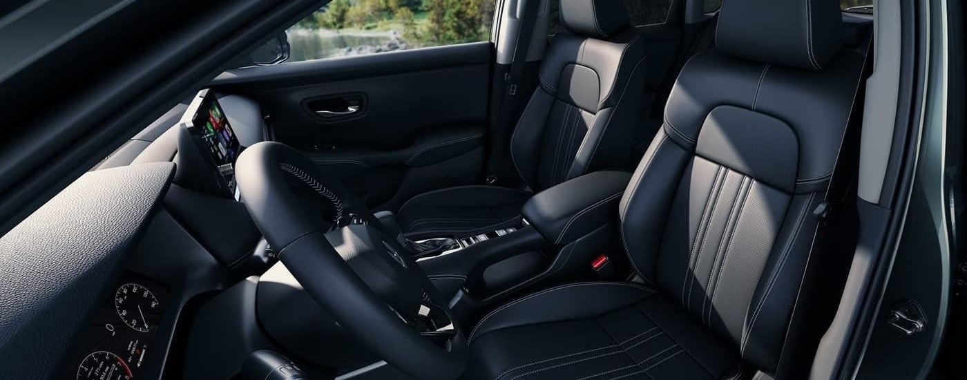 The black interior of a 2024 Honda HR-V shows the front seating and the steering wheel.