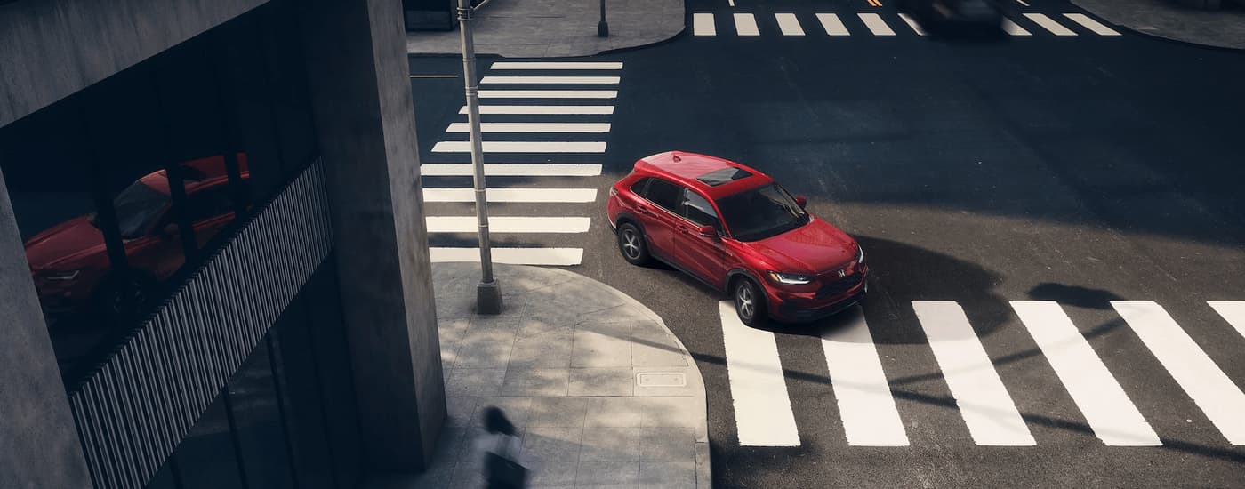 A red 2024 Honda HR-V EX-L is shown turning onto a city street.