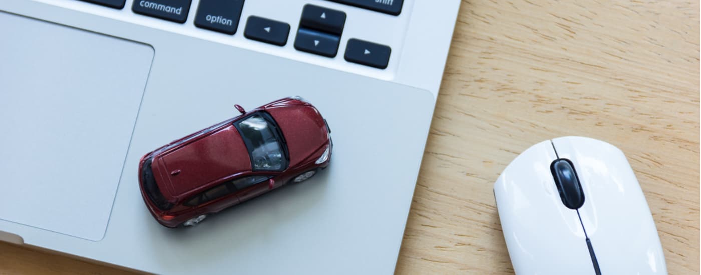 A red toy car is shown on top of a laptop keyboard at a Honda dealer in Midland.