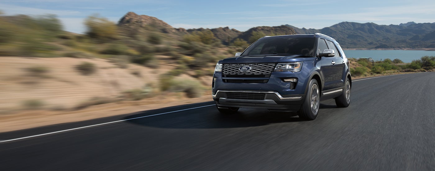 A blue 2018 Ford Explorer is shown driving on an open road.