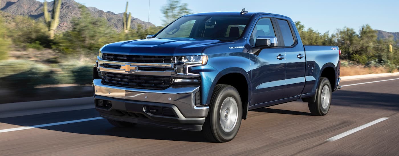 A blue 2019 Chevy Silverado 1500 is shown driving on an open road after viewing used trucks for sale near Big Spring.