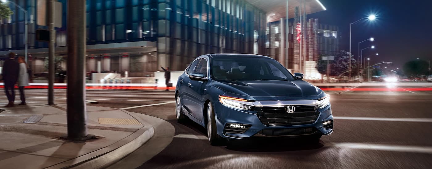 A blue 2022 Honda Insight Touring is shown driving on a city street.