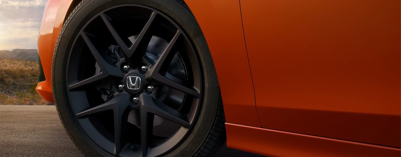 The rim and tire are shown on an orange 2022 Honda Civic Si.