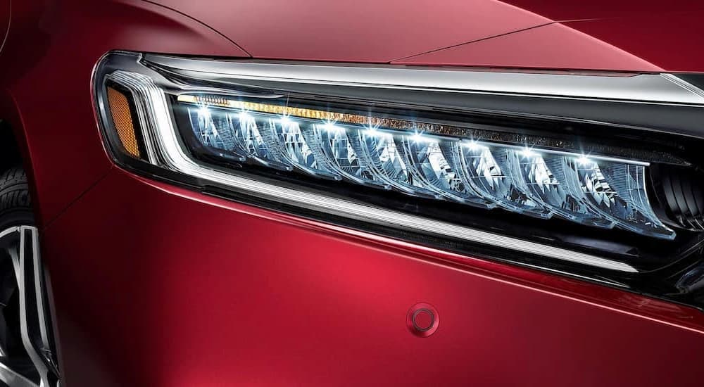 A close up of the headlight is shown on a red 2022 Honda Accord for sale.
