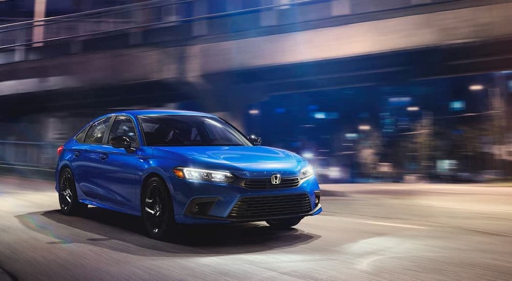A blue 2023 Honda Civic Sport is shown driving on a city street after leaving a Honda dealer near Pecos, TX.