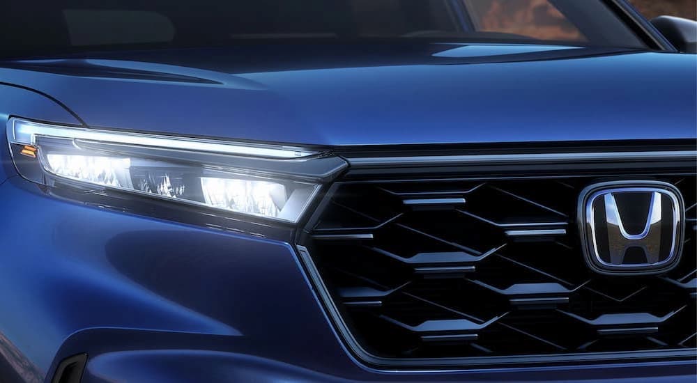 A close up of the front of 2023 Honda CR-V shows the headlight and grille.