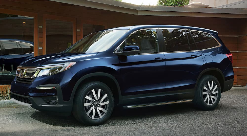 A blue 2022 Honda Pilot EX-L is shown parked in a driveway after visiting a Honda dealer in Midland.
