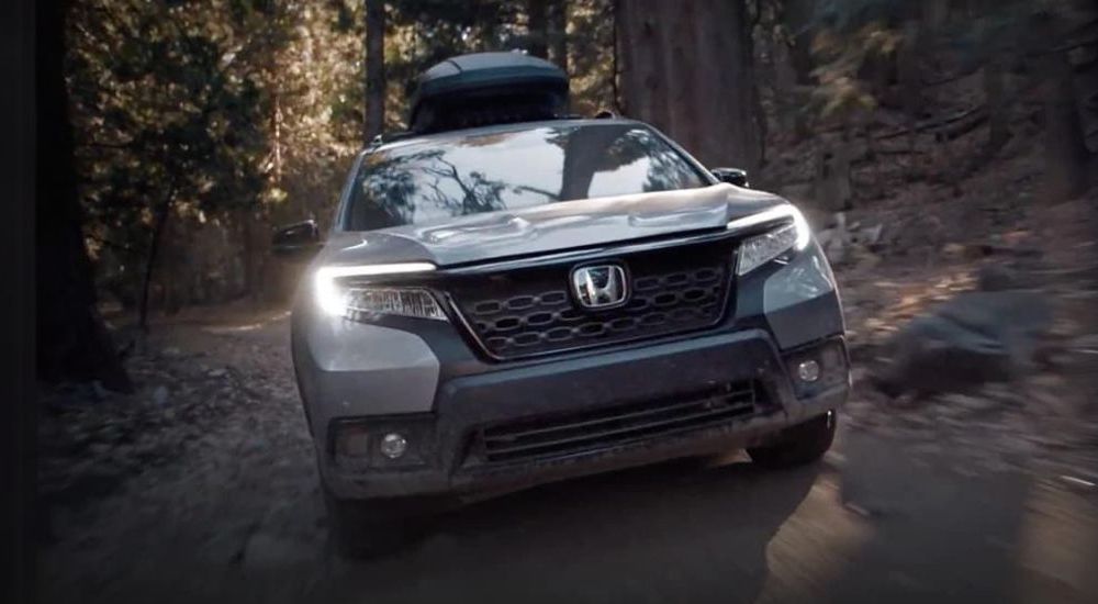 A silver 2021 Honda Passport is shown driving on a trail after looking at used SUVs for sale.