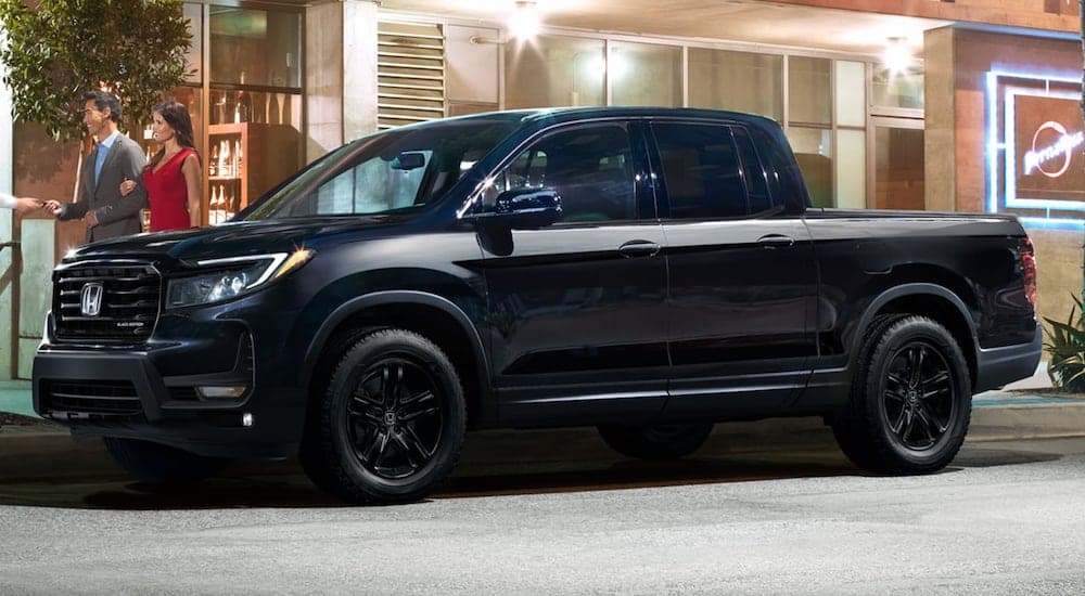 A black 2024 Honda Ridgeline is shown from the side on a city street.