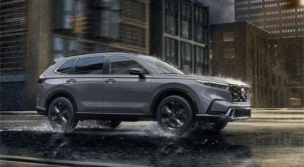 A grey 2023 Honda CR-V is shown from the side in the rain near a dealer that has used SUVs for sale near Andrews.