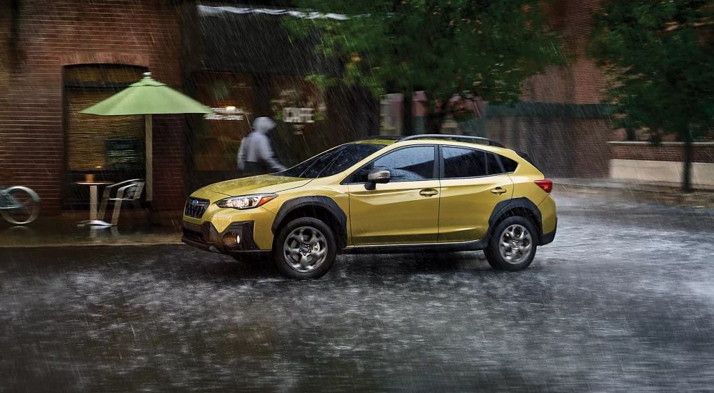 A yellow 2023 Subaru Crosstrek driving through heavy rain.