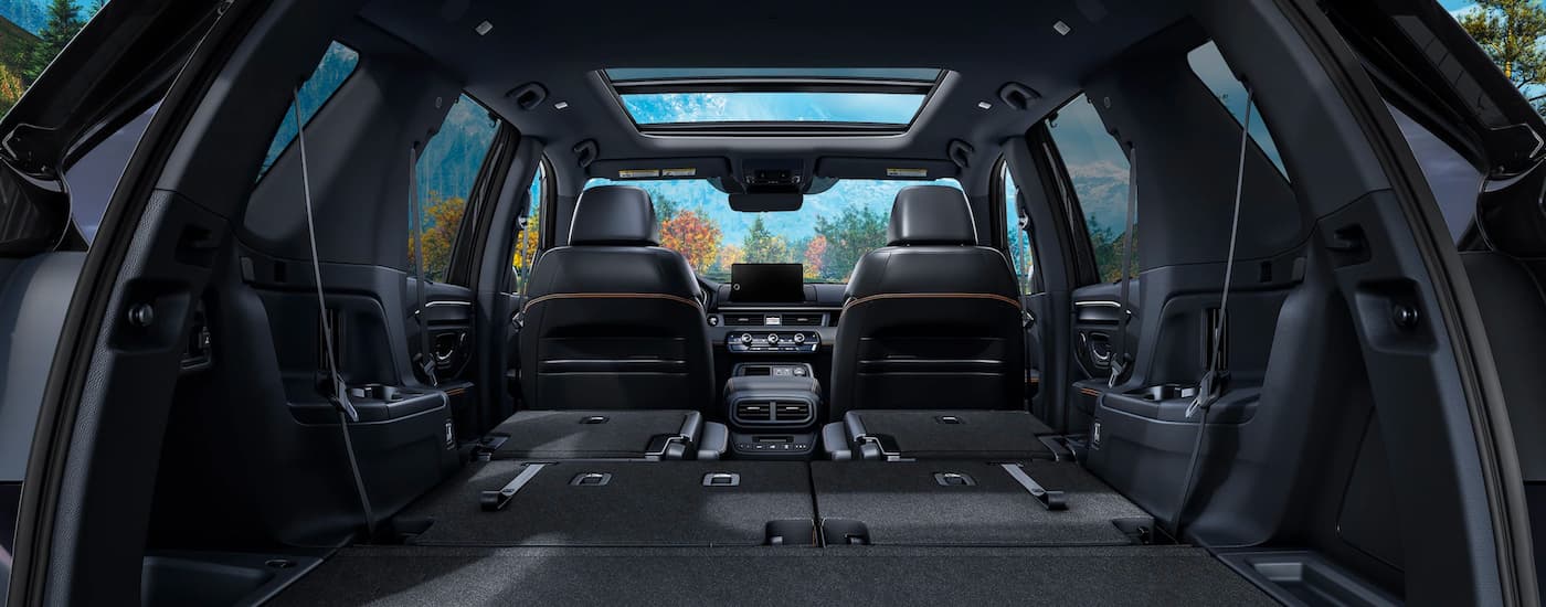 The black interior of a 2023 Honda Pilot shows the rear cargo area with the seating folded down.