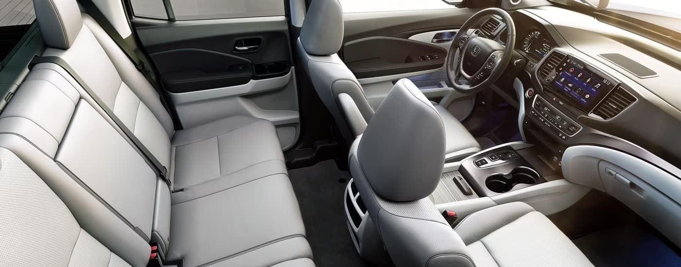The grey leather interior of a 2023 Honda Ridgeline shows two rows of seating.