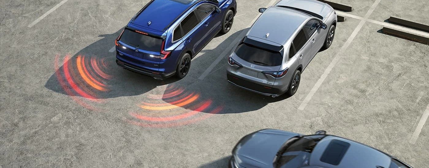The Honda Sensing feature on a blue 2024 Honda CR-V is shown in a parking lot.