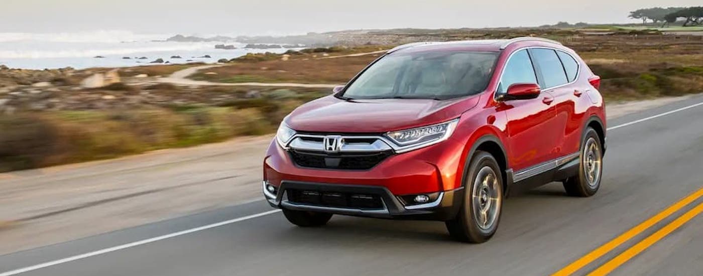 A red 2018 Honda CR-V is shown driving on an open road after viewing used cars for sale near Odessa.