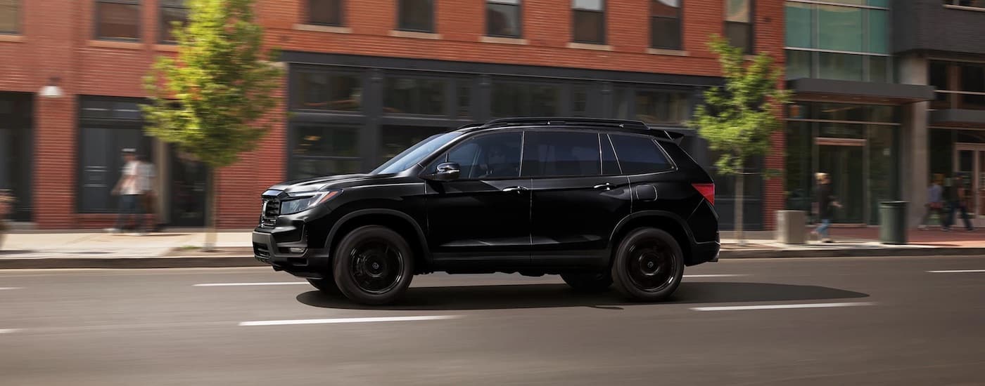 A black 2023 Honda Passport is shown from the side on a city street after leaving a dealer that has used SUVs for sale near Odessa.