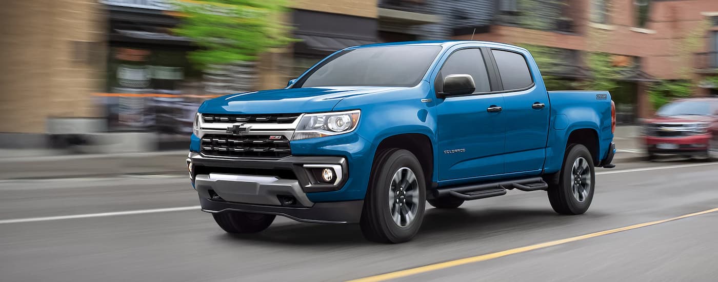 A blue 2022 Chevy Colorado Z71 is driving on a city street after viewing used trucks for sale near Odessa.