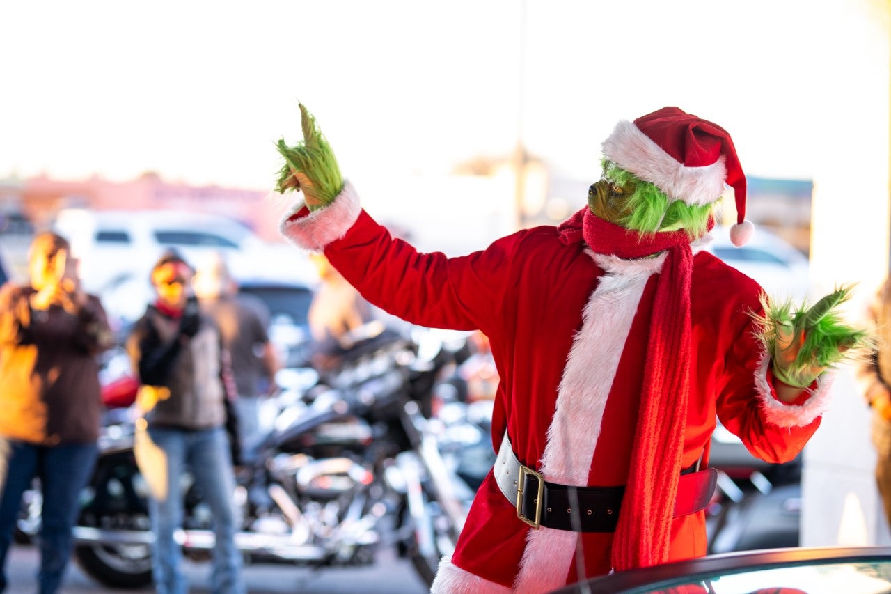 Grinch in a Santa Suit Making Rock On Signs with Hands to the Crowd